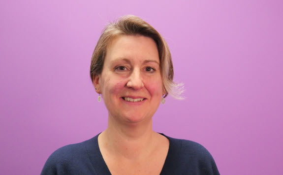 Photograph of Claire Walker with a purple background.
